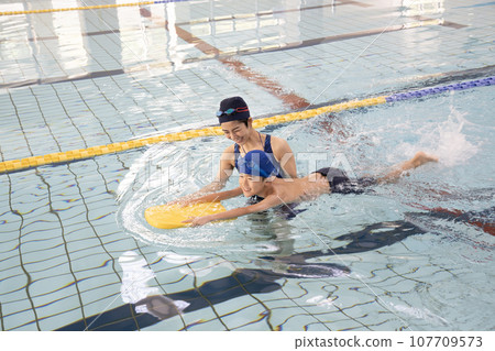 Swimming coach teaching a boy how to swim in the pool 107709573