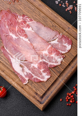 Slices of delicious smoked jamon or prosciutto with salt, spices and herbs Slices of delicious smoked jamon or prosciutto with salt, spices and herbs 107709691