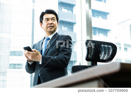 中年企業主在辦公室看智慧型手機 中年企業主在辦公室看智慧型手機 107709900