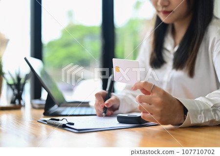 Select focus on woman hand holding credit card and writing notes. Electronic money, contactless payment concept 107710702