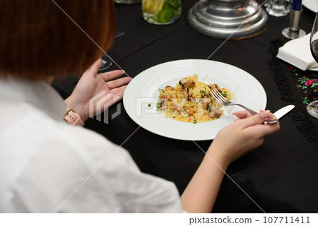 women in a restaurant going to eat paella with chicken and mussels women in a restaurant going to eat paella with chicken and mussels 107711411