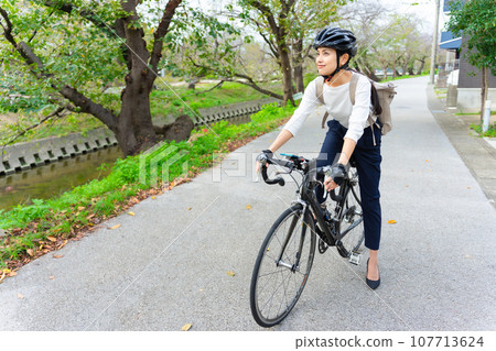 一位穿著商務休閒服騎公路自行車的年輕女子 107713624