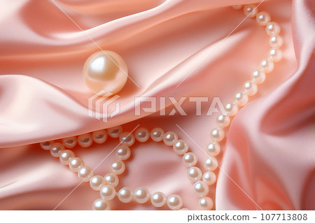 Pearls background. Pile of white natural pearls on pink silk closeup. Pearl on smooth elegant silky fabric texture 107713808