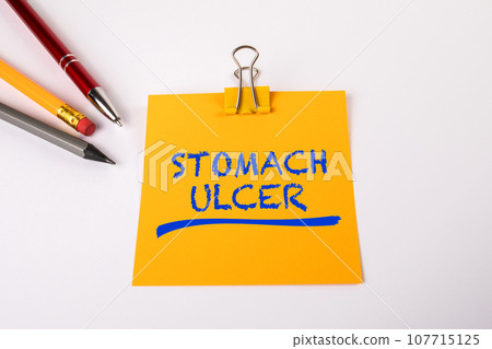 STOMACH ULCER. Yellow notepad and pen on white office table 107715125