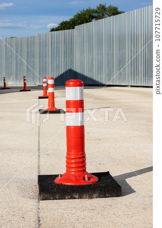 Orange restrictive poles on the road closeup Orange restrictive poles on the road closeup 107715729