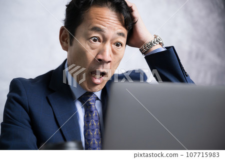 一個看起來像公司總裁的男人的特寫鏡頭,看著電腦,對股票、投資、日圓兌美元疲軟、工作成果等感到驚訝。 一個看起來像公司總裁的男人的特寫鏡頭,看著電腦,對股票、投資、日圓兌美元疲軟、工作成果等感到驚訝。 107715983