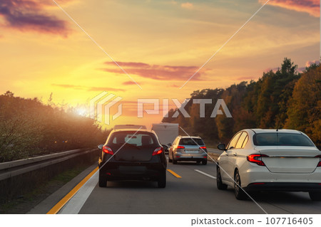 Back tail view of many cars stuck in row at highway city street road traffic jam warm sunset time. Automobile accident vehicle rush hour collapse. Town transport commute infrastructure blockage strike Back tail view of many cars stuck in row at highway city street road traffic jam warm sunset time. Automobile accident vehicle rush hour collapse. Town transport commute infrastructure blockage strike 107716405