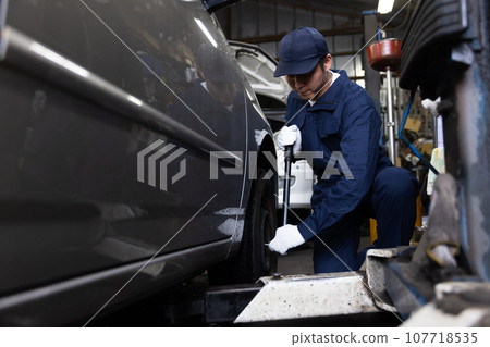 Mechanic inspecting a car Mechanic inspecting a car 107718535