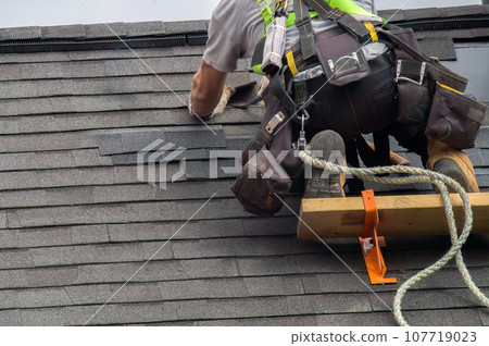 Roofer Construction Worker Ensuring Roof Maintenance with Security Rope 107719023