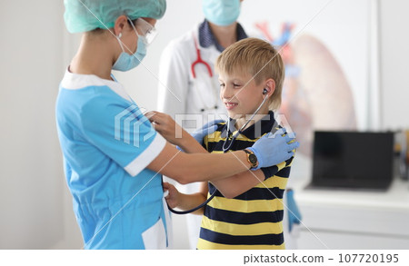 Child at doctor's appointment tries on stethoscope Child at doctor's appointment tries on stethoscope 107720195