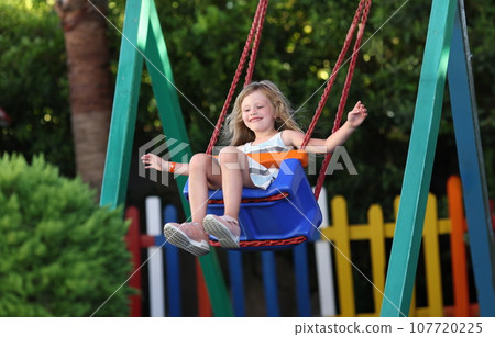 Happy little girl swinging on swing concept 107720225