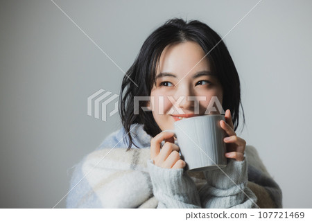 A woman drinking a hot drink A woman drinking a hot drink 107721469