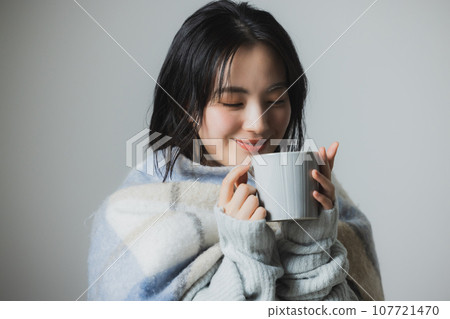 A woman drinking a hot drink A woman drinking a hot drink 107721470