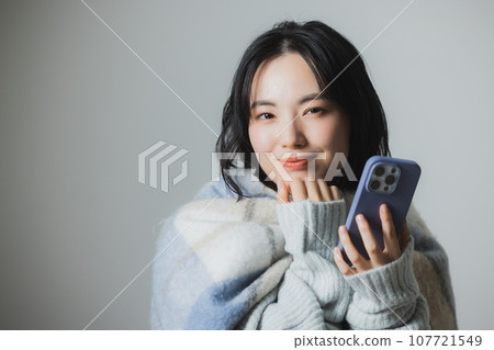 A young woman operating a smartphone 107721549