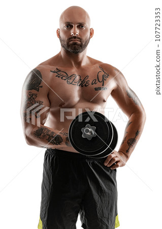 Athletic bald, tattooed man in black shorts is posing with a dumbbell isolated on white background. Close-up portrait. 107723353