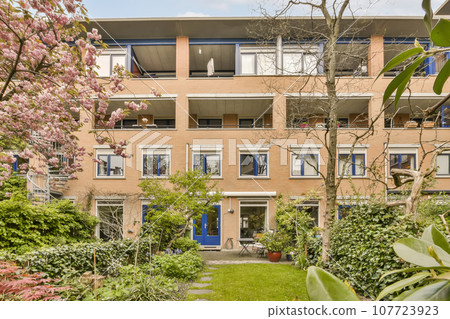an apartment building with trees and bushes in the foregrounding area, amsterdam, netherlands - stockfoorenlm com 107723923