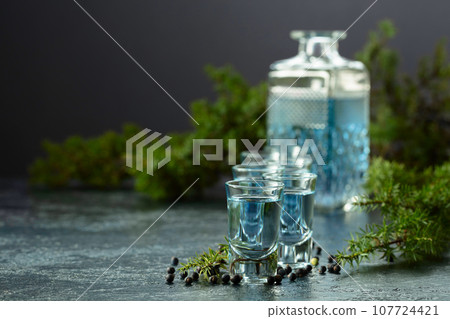 Gin and juniper branches on a vintage dark blue table. 107724421