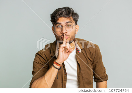 Indian man presses finger to lips make silence gesture sign do not tells secret stop gossip privacy 107724764