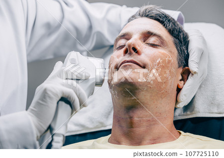 Skin doctor using HIFU resurfacing facial skincare treatment technology with adult male to reduce wrinkles and scars at anti aging clinic 107725110