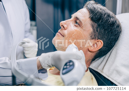 Skin doctor using RF Thermage resurfacing facial skincare treatment technology with adult male to reduce wrinkles and scars at anti aging clinic Skin doctor using RF Thermage resurfacing facial skincare treatment technology with adult male to reduce wrinkles and scars at anti aging clinic 107725114