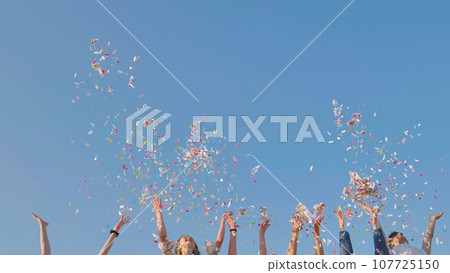 Tossing colorful paper confetti from the hands of young people. Tossing colorful paper confetti from the hands of young people. 107725150