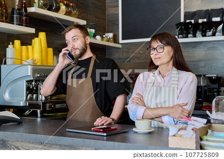 Team male and woman talking, working, using phone, coffee shop Team male and woman talking, working, using phone, coffee shop 107725809
