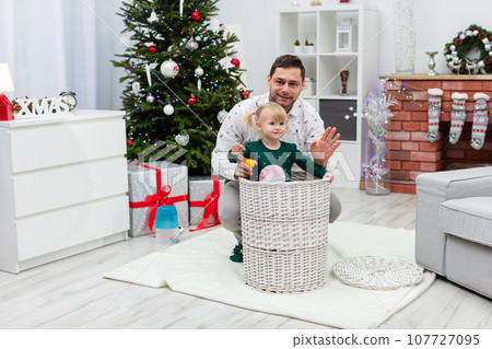 A dad and his little girl play in a festively decorated room A dad and his little girl play in a festively decorated room 107727095