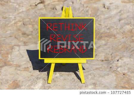 Rethink revise rebrand symbol. Concept word Rethink Revise Rebrand on beautiful blackboard. Beautiful red stone background. Business brand motivational rethink revise rebrand concept. Copy space. 107727485