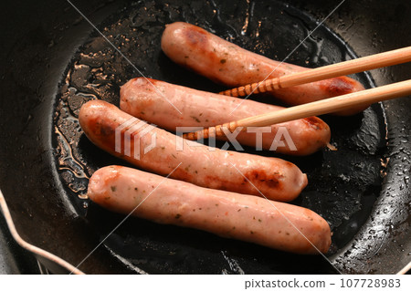 Sausage frying in a frying pan 107728983