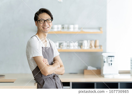 Cafe clerk smiling and folding his arms Cafe clerk smiling and folding his arms 107730985