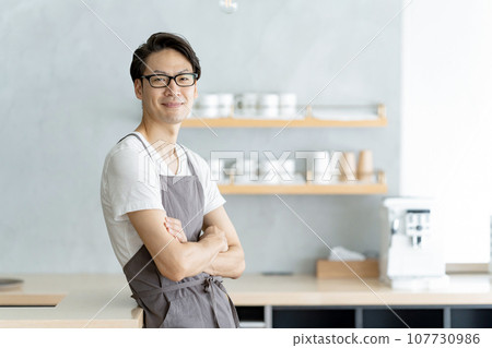 Cafe clerk smiling and folding his arms Cafe clerk smiling and folding his arms 107730986