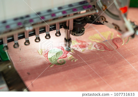 Close up of embroidery machine making patterns on textiles Close up of embroidery machine making patterns on textiles 107731633