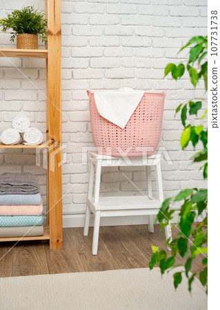 Pink plastic laundry basket in a bathroom Pink plastic laundry basket in a bathroom 107731738
