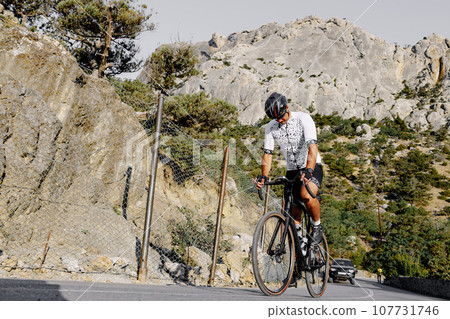 Professional road bicycle racer in action on mountain road 107731746
