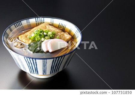 Kitsune 蕎麥麵配上炸豆腐、魚糕、裙帶菜和蔥，在黑色背景下拍攝 107731850