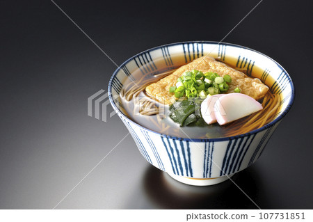 Kitsune 蕎麥麵配上炸豆腐、魚糕、裙帶菜和蔥,在黑色背景下拍攝 Kitsune 蕎麥麵配上炸豆腐、魚糕、裙帶菜和蔥,在黑色背景下拍攝 107731851