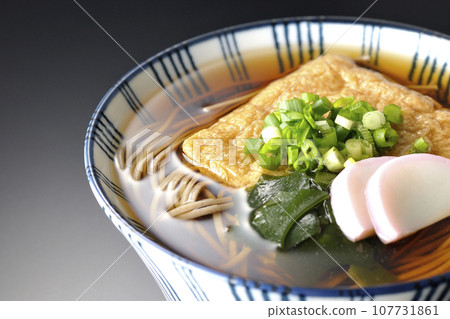 Kitsune 蕎麥麵配上炸豆腐、魚糕、裙帶菜和蔥，在黑色背景下拍攝 107731861