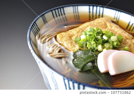 Kitsune 蕎麥麵配上炸豆腐、魚糕、裙帶菜和蔥,在黑色背景下拍攝 Kitsune 蕎麥麵配上炸豆腐、魚糕、裙帶菜和蔥,在黑色背景下拍攝 107731862