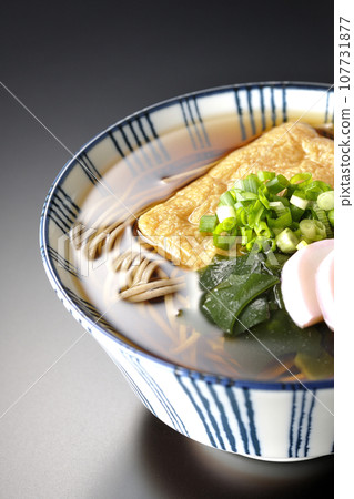 Kitsune 蕎麥麵配上炸豆腐、魚糕、裙帶菜和蔥，在黑色背景下拍攝 107731877