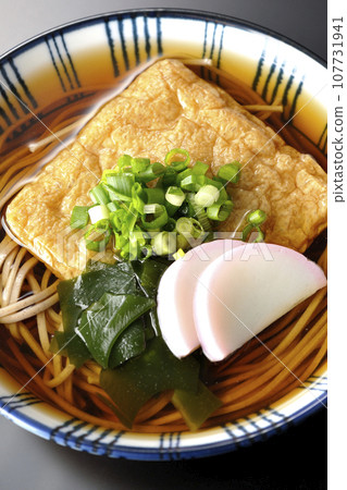 黑色背景下的狐狸蕎麥麵,上面放著炸豆腐、魚板、裙帶菜和蔥 黑色背景下的狐狸蕎麥麵,上面放著炸豆腐、魚板、裙帶菜和蔥 107731941