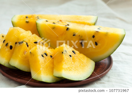 Yellow watermelon sliced on wooden background Yellow watermelon sliced on wooden background 107731967