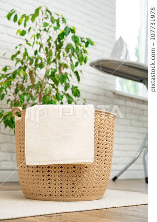 Beige plastic basket for laundry in a room Beige plastic basket for laundry in a room 107731978