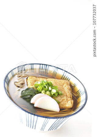 Kitsune 蕎麥麵上面放著炸豆腐、魚糕、裙帶菜和蔥，在白色背景下拍攝 107732037