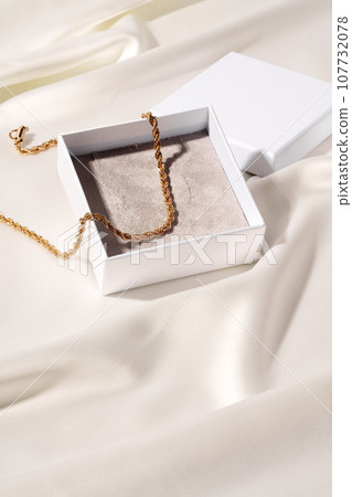 Golden chain in jewel box on silk background Golden chain in jewel box on silk background 107732078