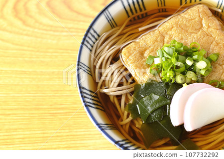 An overhead shot of kitsune soba topped with fried tofu, kamaboko, seaweed, and green onions An overhead shot of kitsune soba topped with fried tofu, kamaboko, seaweed, and green onions 107732292