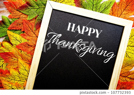 Happy Thanksgiving text on blackboard decorate with maple leaves and pumpkin on wooden background 107732393