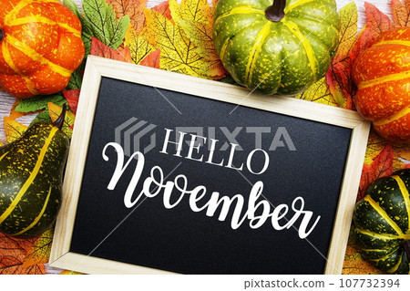 Hello November text on blackboard decorated with maple leaves on wooden background 107732394