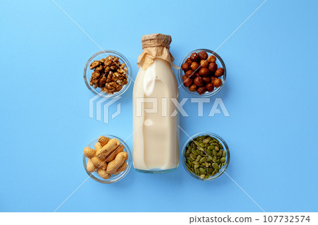 Vegetable milk concept with milk bottle and bowls with grains on blue background top view 107732574