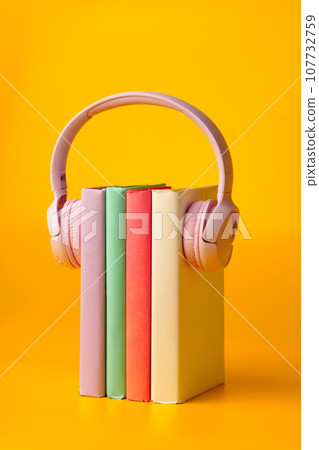 Modern headphones with hardcover books on yellow background 107732759