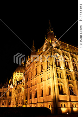 Evening photo of the Parliament building in Budapest. The majestic Saxon architecture is illuminated with warm yellow light 107733363